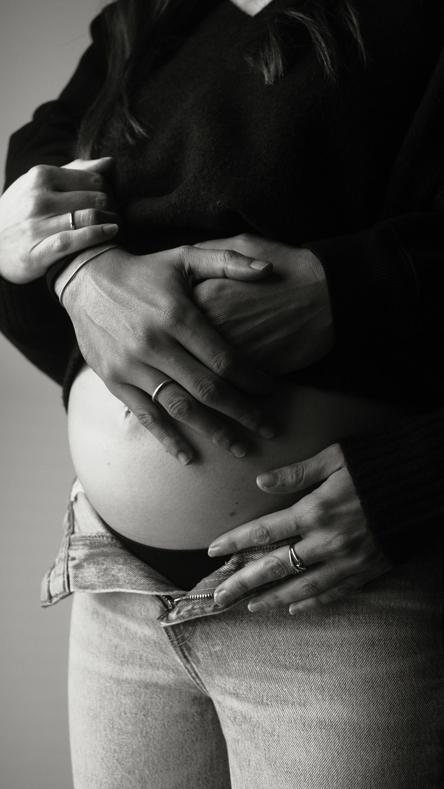 Hands resting gently on a pregnant belly, in black and white